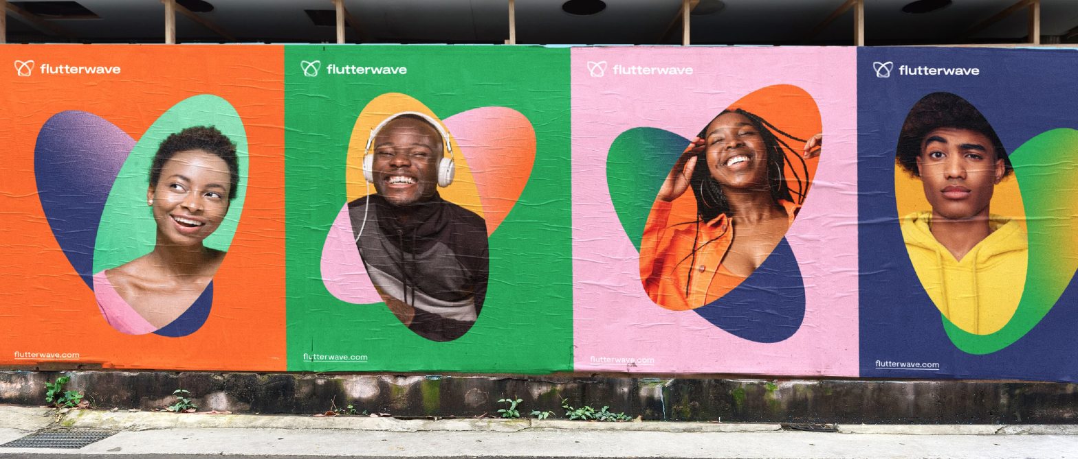 Demo outdoor billboard advertising campaign for Flutterwave featuring four diverse, smiling individuals inside colorful abstract heart-shaped cutouts against orange, green, pink, and navy blue backgrounds.